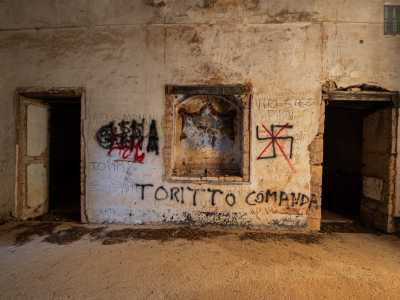 I muri sono cosparsi di scritte fatte con bombolette spray, che lasciano spazio a una nicchia che custodisce un antico stemma su sfondo ocra
